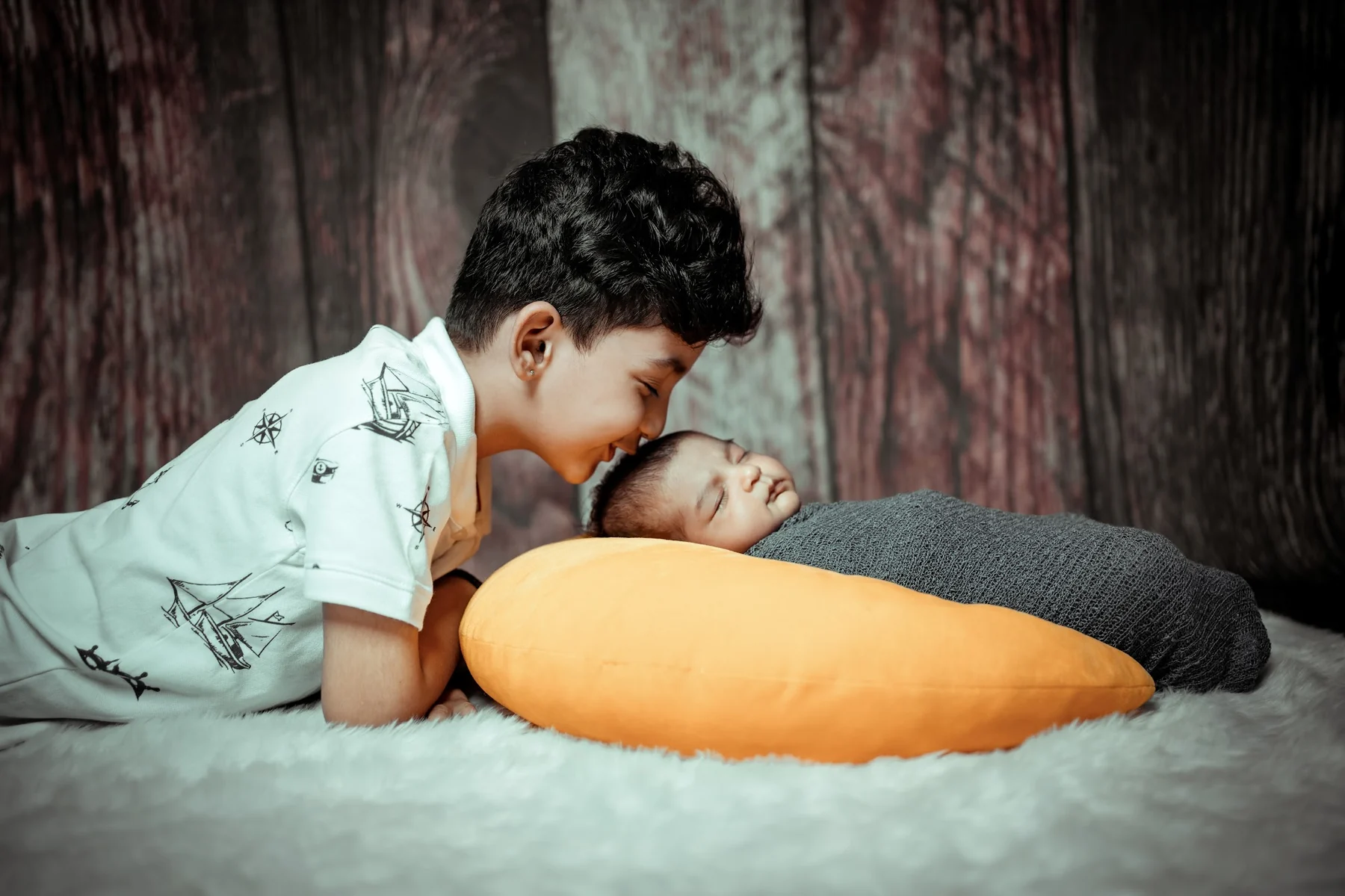 Older Brother Gently Kissing Newborn Baby Sister